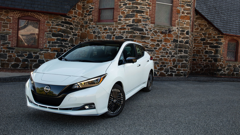 A white Nissan leaf in front of a building