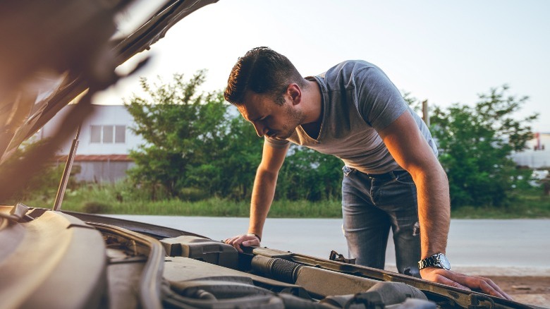 A man looking into his car's open engine bay