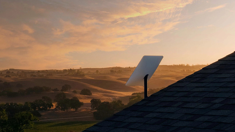 Starlink dish mounted on slanted roof facing the countryside