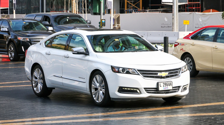 A white Chevrolet Impala.parked on a road.