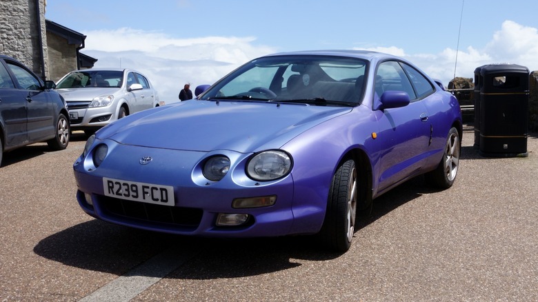 A blue Toyota Celica with a UK license plate parked on pavement.