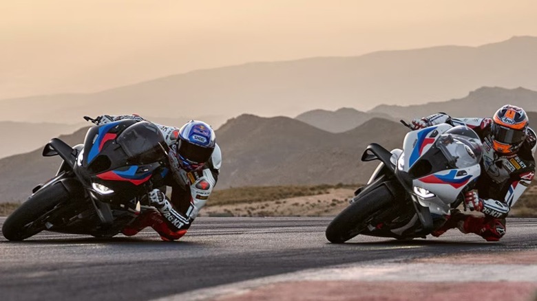 A pair of BMW S 1000 RR motorcycles racing on a track. Both are leaned over.