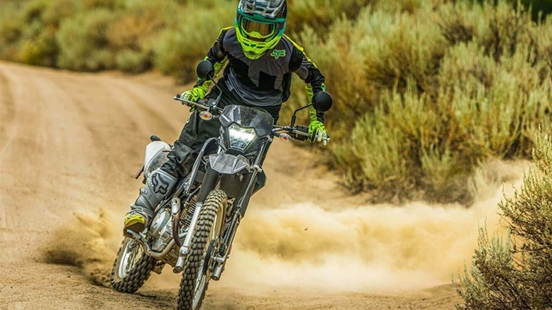 A Battle Gray Kawasaki KLX230 S sliding on a dirt road