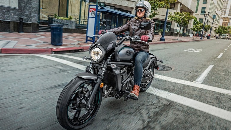 A lady riding a Kawasaki Vulcan S Cafe on a city street.