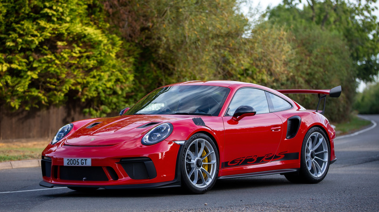 A red Porsche 911 GT3 on a street in front of trees