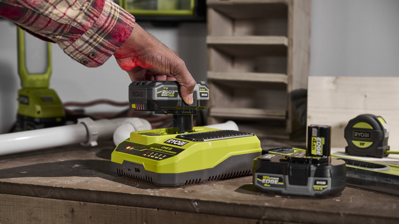 Hand plugging in a RYOBI ONE+ battery into the Rapid Charger