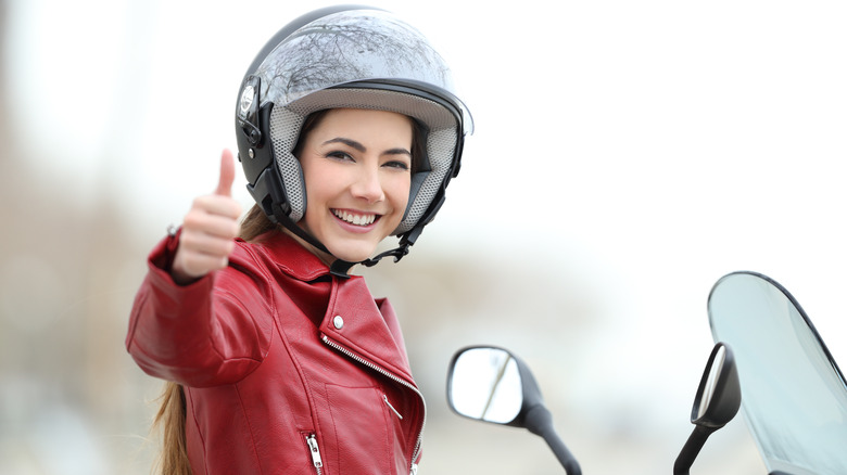 Woman holding thumbs up on motorcycle