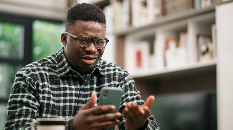 person holding smartphone looking frustrated