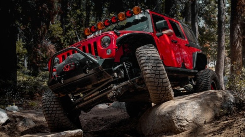 Red jeep off-roading down a rocking trail