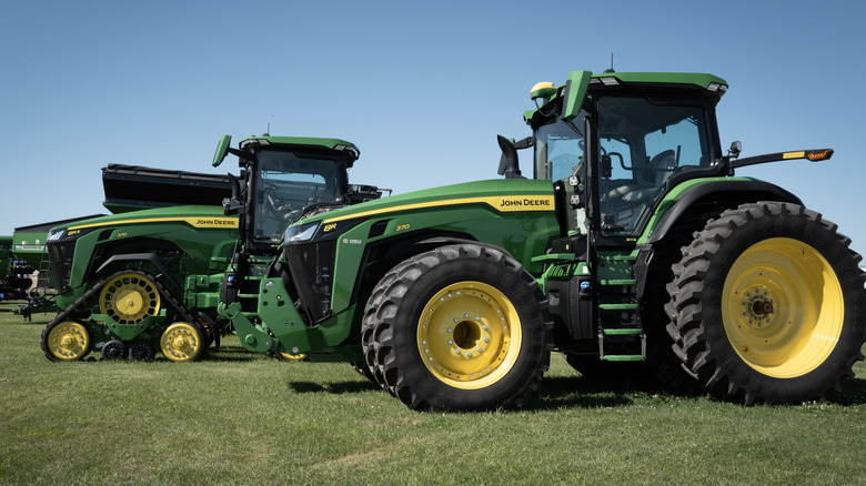 Green and yellow John Deere tractors parked on grass.