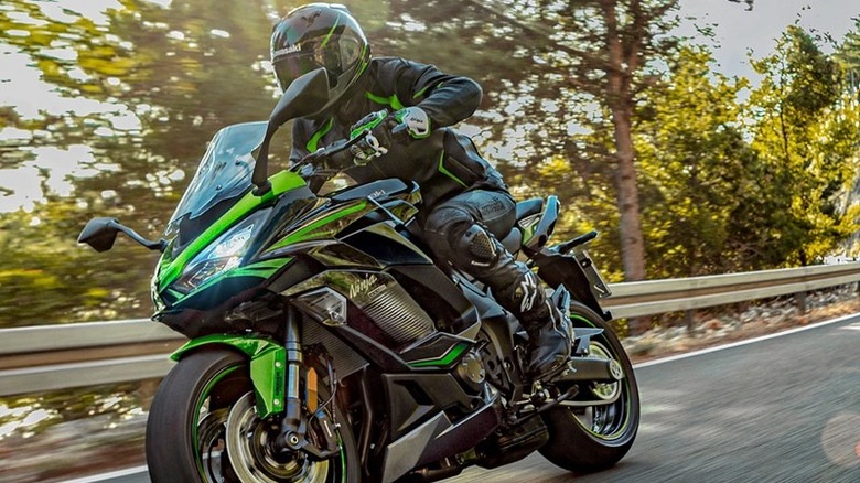 A 2025 Kawasaki Ninja 1100 SX speeds down a rural highway