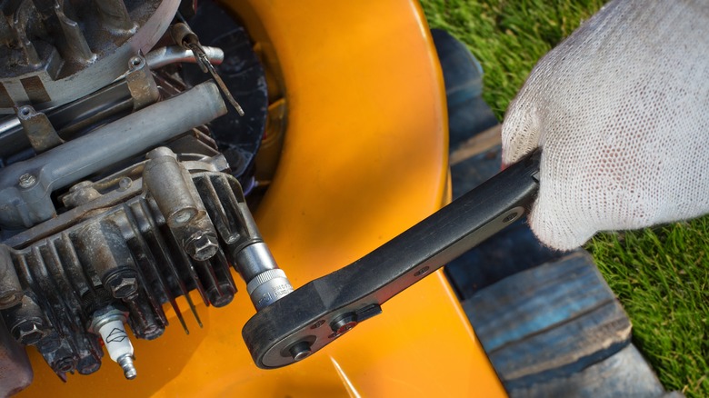 person repairing lawn mower engine