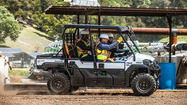 Three workers riding in a Kawasaki Mule Pro DXT at the jobsite