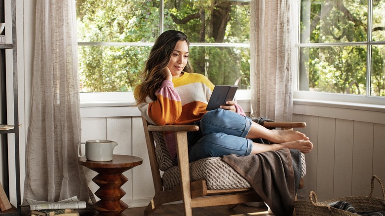 Person sitting in a sun room reading a Kindle