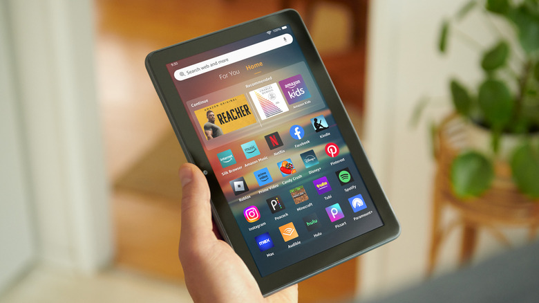 Person holding Amazon Fire Tablet, with Kindle and Audible apps