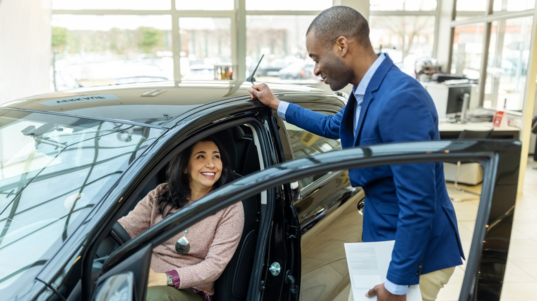 Man showing car to woman at dealership