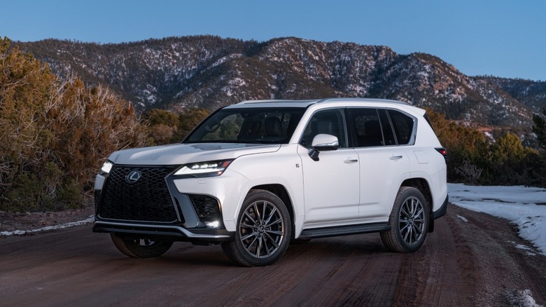 White Lexus LX 600 F SPORT parked near snowy mountains