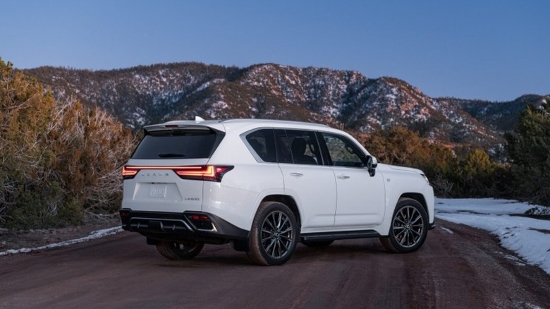 White Lexus LX 600 F SPORT parked near snowy mountains