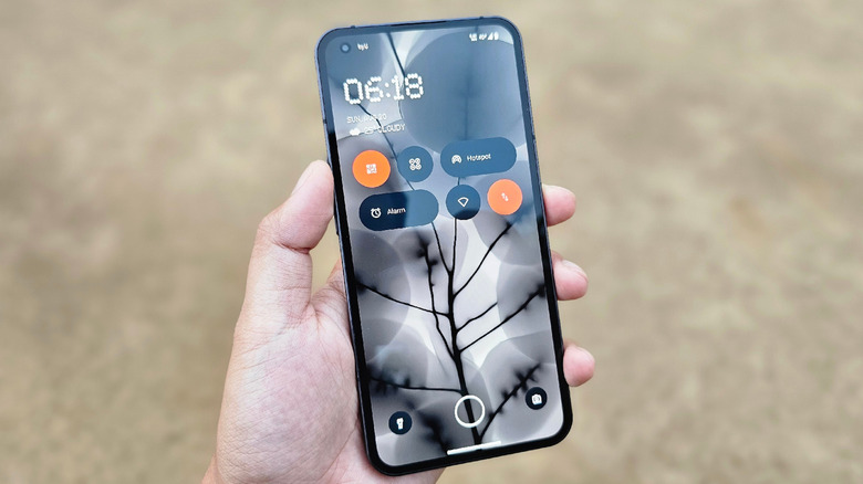 Hand holding Nothing Phone 1 showing lock screen widgets