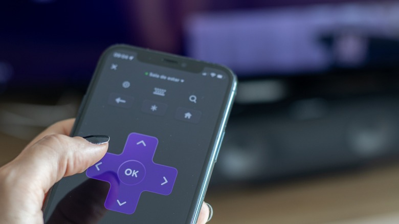 person with black nail polish using Roku phone app