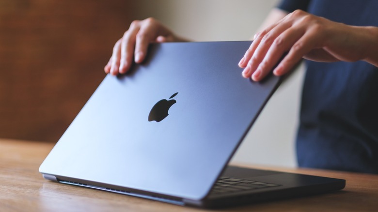 Person opening the lid of a MacBook