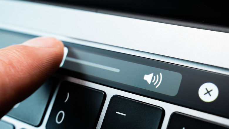 person pressing the speaker button on a Mac's touch bar