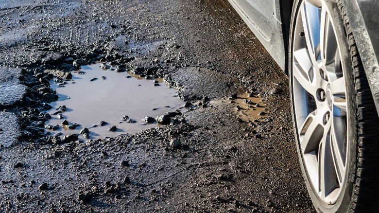 A pothole with a car's wheel near it