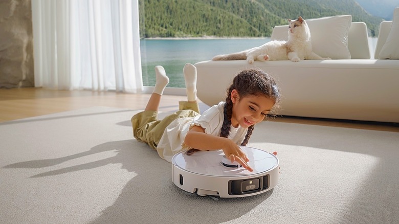 A little girl on the floor examining a Dreame robovac.