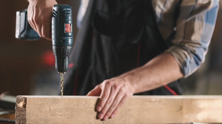 Person drilling square timber