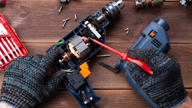 Person repairing torn apart power drill