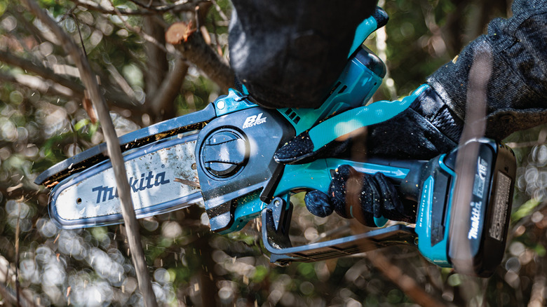 Person cutting through small brush with a Makita pruning saw