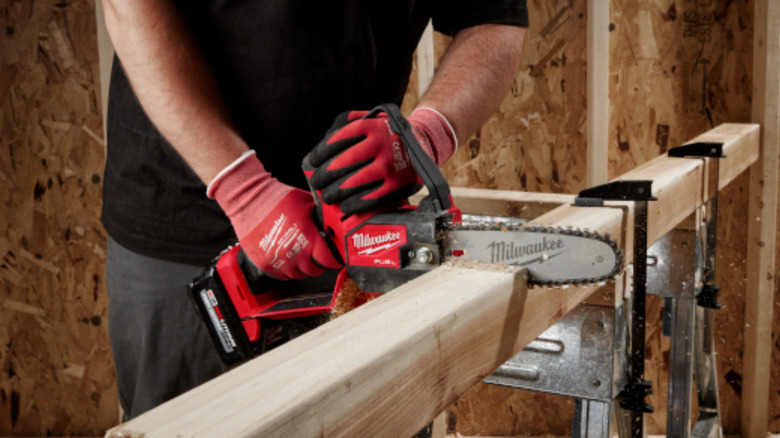 Person cutting through a piece of lumber with a Milwaukee pruning saw