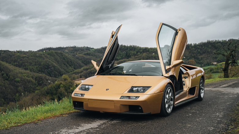 A golden Lamborghini Diablo with its doors open skyward.