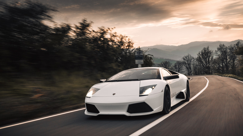 A white Lamborghini Murcielago on the road at sunset.