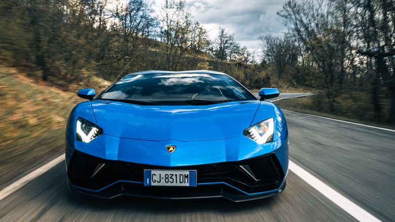 A blue Lamborghini Aventador Ultimae on the road.