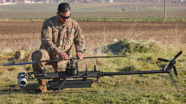 A soldier crouching over a the Ghost-X in a field during testing