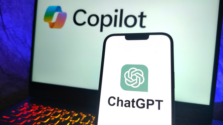 Smartphone showing ChatGPT logo in front of laptop showing Copilot logo