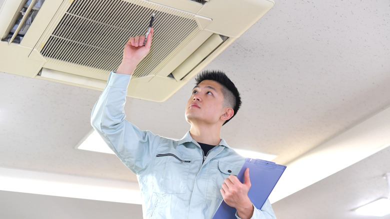 A man on work clothes doing maintenance on the air conditioner