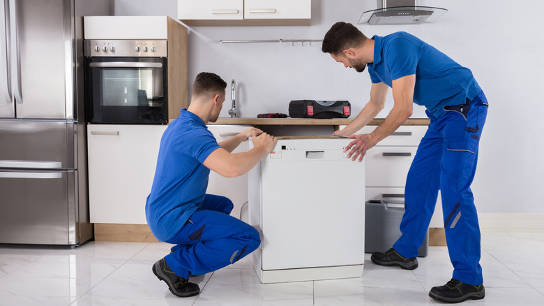 Two male Movers placing a Dishwasher in the kitchen