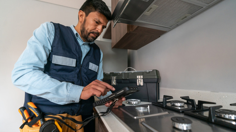 A supervisor making gas inspection at a house checking for leakages on the gas cooker