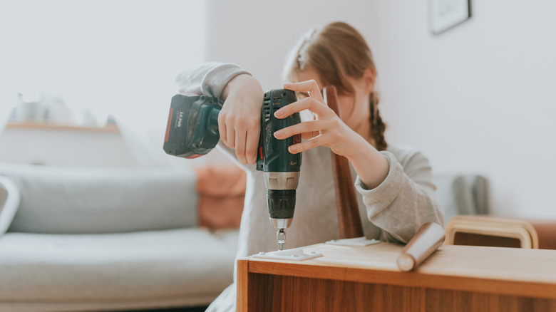 Woman using cordless drill on furniture