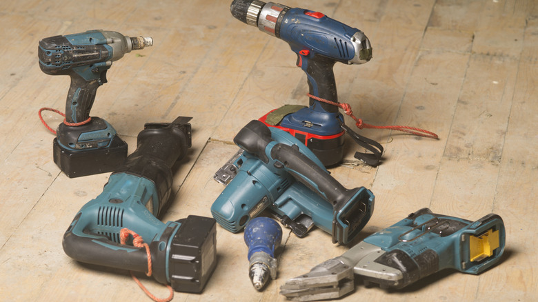 Collection of cordless power drills on wooden floor