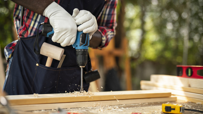 Man using a long drill bit on wood