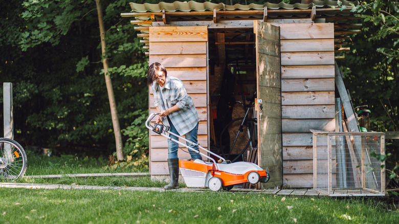 Woman getting lawn mower out of shed