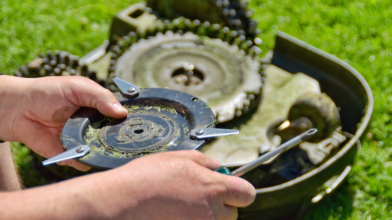 Man changing blade on lawn mower