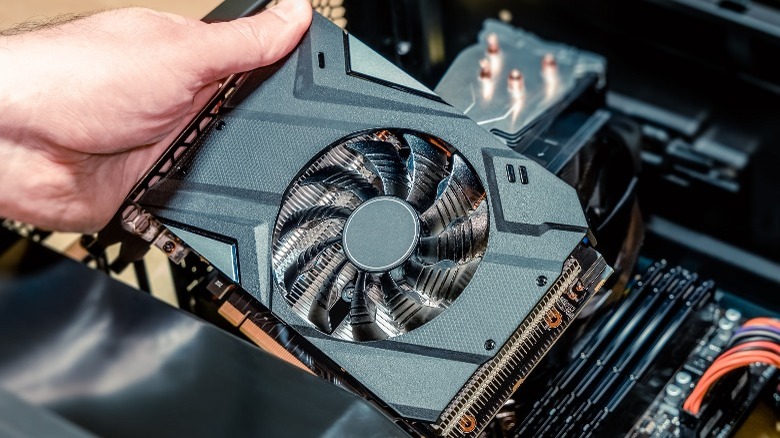 Person's hand holding single fan graphics card