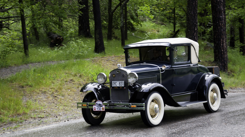 1930 Ford Model A driving on road, front-left three-quarter view