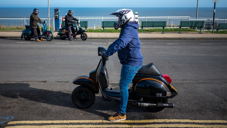 Scooter riders parked on the side of the road