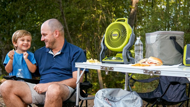 Father and son next to fan