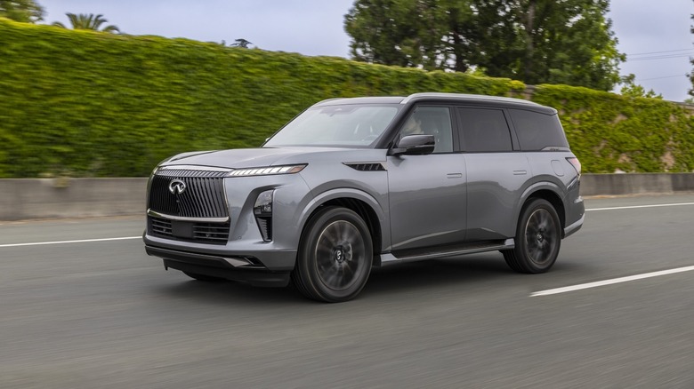 2025 Infiniti QX80 driving on a road with trees in the background